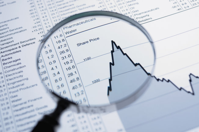 Magnifying glass and descending line graph and list of share prices